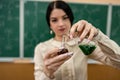 female student is practicing in a chemistry classroom with flasks on of a board with formulas. Royalty Free Stock Photo