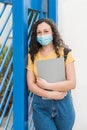 Female student or school girl in mask with backpack and folder over blue gate Royalty Free Stock Photo