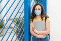 Female student or school girl in mask with backpack and folder over blue gate Royalty Free Stock Photo