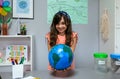 Female student showing a handmade globe world at ecology classroom