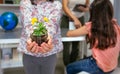 Female student showing to camera a pansy plant in ecology classroom