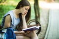 Young Female student sitting on bench and reading book in park Royalty Free Stock Photo