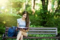 Young Female student sitting on bench and reading book in park Royalty Free Stock Photo