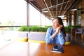 Female student sitting at cafe with smartphone and notebook on table.