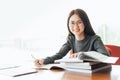 Female student taking notes from a book at library, Young asian woman sitting at table doing assignments in college library Royalty Free Stock Photo