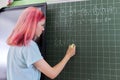 Female student teenager at a math lesson writing in chalk on a blackboard Royalty Free Stock Photo