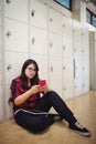 Female student using mobile phone in locker room Royalty Free Stock Photo