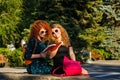 Female students read a book in park.