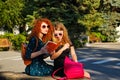 Female students sister reading a book in park.