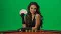 Female in studio on chroma key green screen isolated background. Woman in black dress at the blackjack table posing with Royalty Free Stock Photo