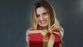 Female studio portrait gray background young beautiful happy generous girl woman holding christmas gift holding red Royalty Free Stock Photo
