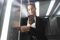 Female in the suit pushing the button it the elevator using gadgets. Close-up photo of an office worker, pushing the lift`s butto