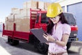 Female supervisor with safety helmet looking through checklist in front of truck carrying boxes Royalty Free Stock Photo
