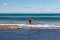 A female surfer entering the sea on Manly Beach