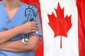 Woman surgeon or doctor with stethoscope on the background of the Canada flag. Health care, surgery and medical concept in Canada