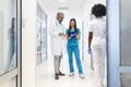 Female Surgeon and Doctor Walk Through Hospital Hallway, They Consult Digital Tablet Computer while Talking about Patient`s Healt Royalty Free Stock Photo