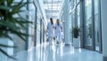 Female Surgeon and Doctor Walk Through White Hospital Hallway