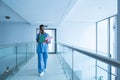 Female surgeon looking at medical reports while talking on mobile phone in corridor