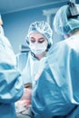 Female surgeon with operating assistants. Surgeons during work. Blue filter. Modern medicine with professional doctors. Royalty Free Stock Photo