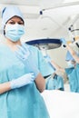 Female surgeon putting on gloves in the operating room, getting prepared, looking at camera Royalty Free Stock Photo