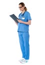 Female surgeon with stethoscope, reading report Royalty Free Stock Photo