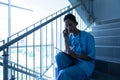 Female surgeon talking on mobile phone while writing on clipboard on staircase Royalty Free Stock Photo