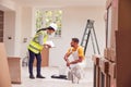 Female Surveyor With Clipboard Meeting With Decorator Working Inside Property