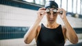 Female swimmer focusing on the race, putting on swimming goggles