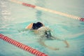 A female swimmer in indoor sport swimming pool trying to dive.