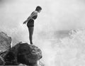 Female swimmer on rock above crashing surf Royalty Free Stock Photo