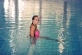 A female swimmer in indoor sport swimming pool. girl in pink sweimsuit in water