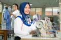 Female tailor in hijab smiles look at camera with a measuring tape worn around her neck using Royalty Free Stock Photo