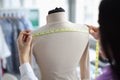 Female tailor takes measurements on mannequin closeup
