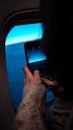 Female taking a photo of the mesmerizing sunset from the airplane window on her smartphone Royalty Free Stock Photo