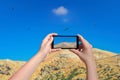 Female taking picture of landscape of mountain birds and sky on smart phone. Birds eagle flying above mountain in mobile phone. Da