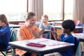 Female teacher and boy clapping hands together in school classroom, smiling and engaged Royalty Free Stock Photo