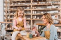 female teacher and child painting ceramic pot in pottery workshop Royalty Free Stock Photo