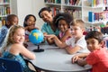 Female teacher and children with globe on table Royalty Free Stock Photo