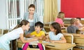 Female teacher controlling group work of interested tweens at lesson Royalty Free Stock Photo