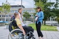Female teacher and children, boy in wheelchair and girl talking outdoor