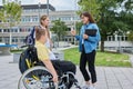 Female teacher and children, boy in wheelchair and girl talking outdoor