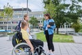Female teacher and children, disabled boy in wheelchair and girl talking outdoor