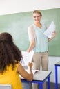 Female teacher handing paper to student