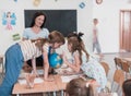 Female teacher with kids in geography class looking at globe. Side view of group of diverse happy school kids with globe Royalty Free Stock Photo