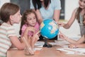 Female teacher with kids in geography class looking at globe. Side view of group of diverse happy school kids with globe Royalty Free Stock Photo