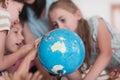 Female teacher with kids in geography class looking at globe. Side view of group of diverse happy school kids with globe Royalty Free Stock Photo