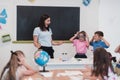 Female teacher with kids in geography class looking at globe. Side view of group of diverse happy school kids with globe Royalty Free Stock Photo