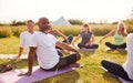 Female Teacher Leading Group Of Mature Men And Women In Class At Outdoor Yoga Retreat