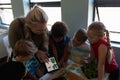 Female teacher looking at pictures of leaves on a tablet computer for a nature study lesson in an el