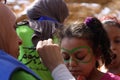 Female teacher painting little girls face in butterfly shape in playground